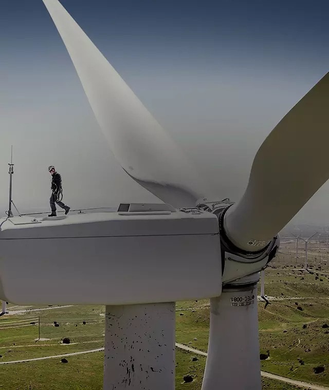 Scenic photo of a worker walking on top of a wind turbine