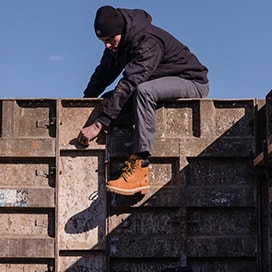 Man working on a ledge wearing Timberland PRO work boots, pants and jacket.