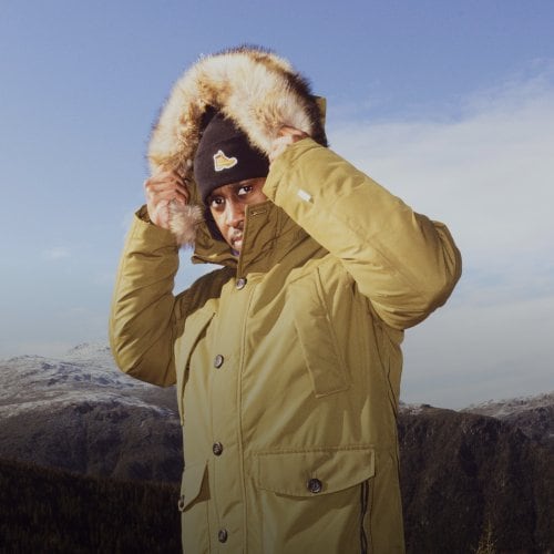 Man wearing Timberland jacket and hat posing in the mountains.