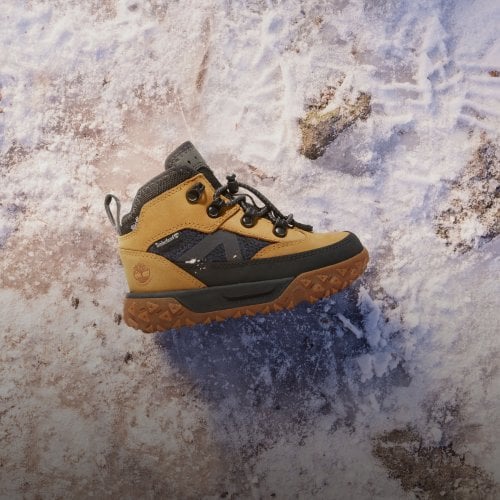 Timberland kids boot positioned on icy snow background.