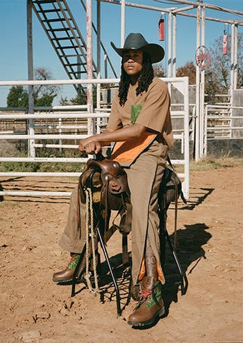 Oklahoma Cowboys Black Pioneer posing with a faux horse at the rodeo wearing Timberland boots