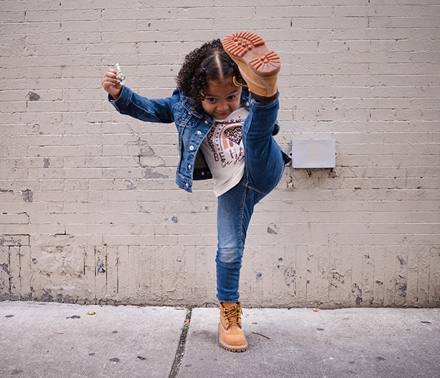 Image of a child kicking wearing Timberland wheat boots