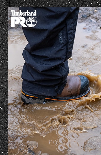Image of a man wearing Timberland PRO Boondock boots stepping in the mud and water
