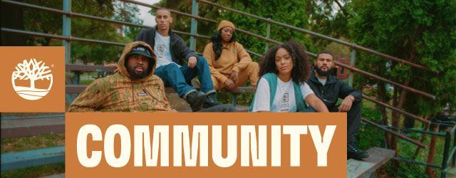 Five young friends, all different races, wearing Timberland, sitting together on bleachers against a backdrop of trees.