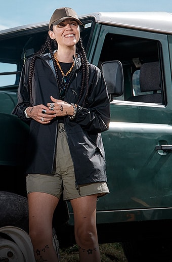 Woman wearing Timberland summer apparel leaning on a car.