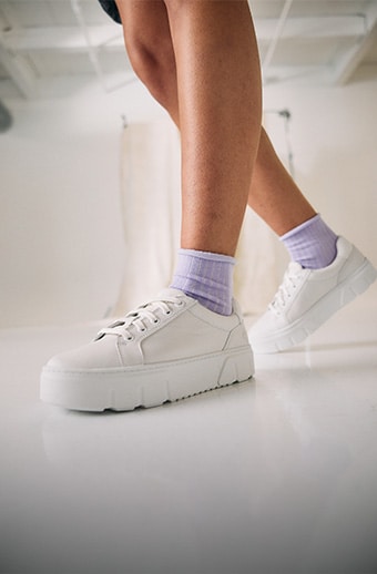 Woman wearing white Timberland sneakers.