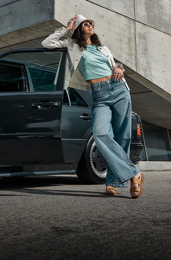 Woman leaning on a car wearing Timberland denim.